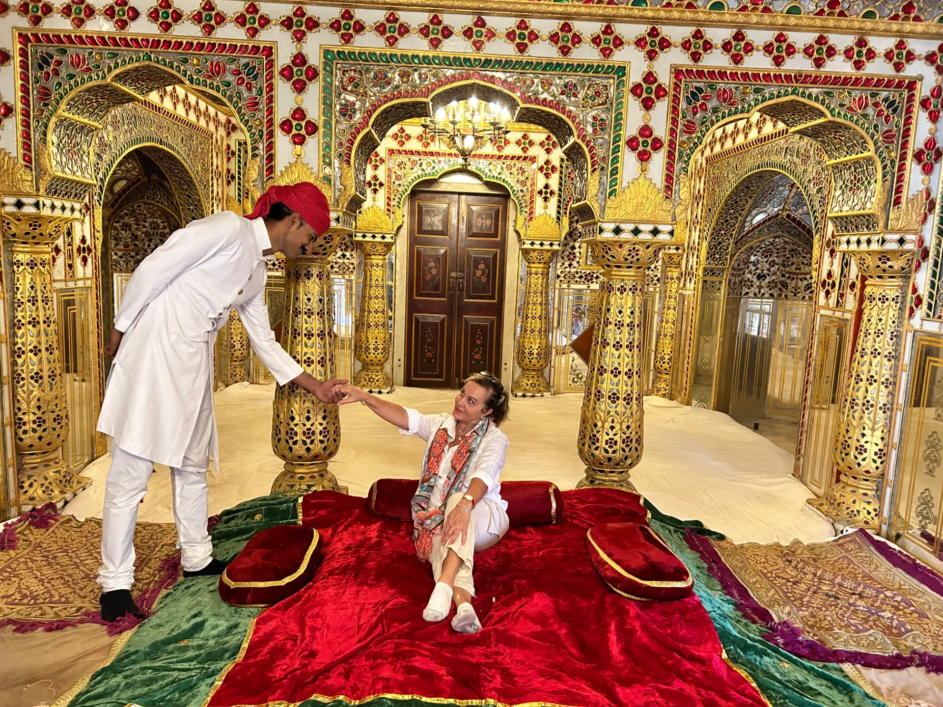 Guest seated on velvet cushions in a gilded jewelled chamber of a Jaipur palace