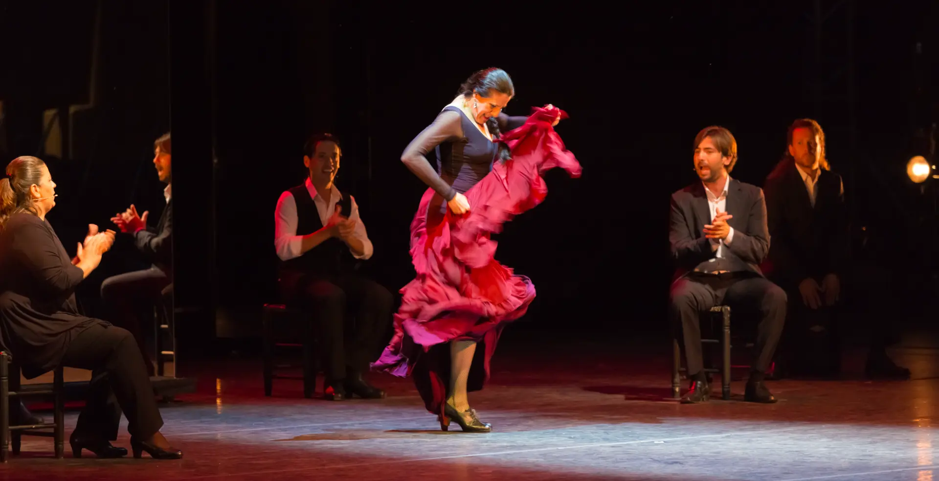Flamenco dancer in a crimson dress performing on stage in Spain
