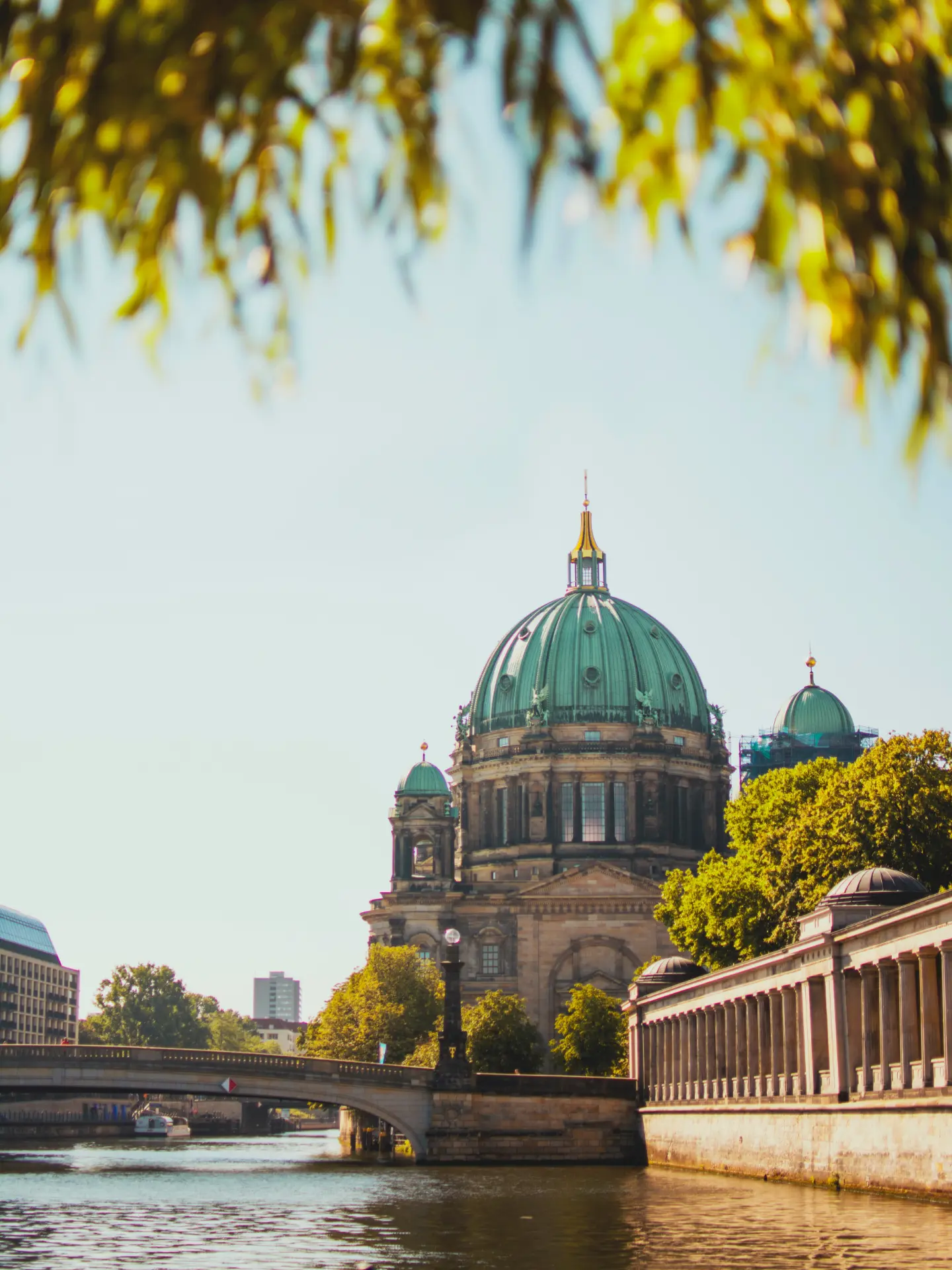 Berlin Cathedral seen across the Spree river framed by autumn leaves