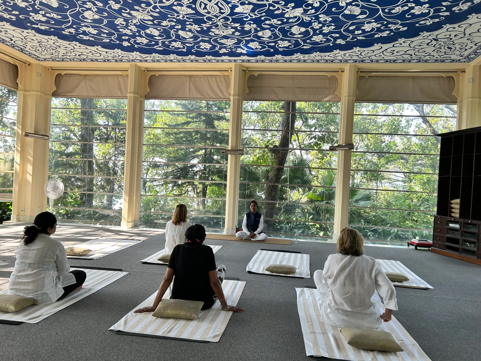 Guests in a yoga session inside a painted pavilion overlooking forest