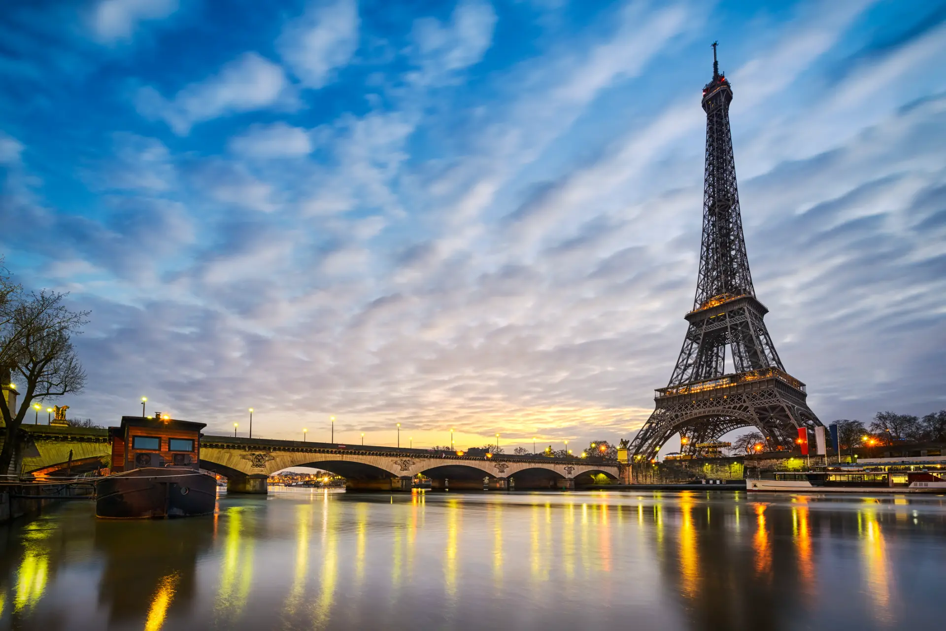 The Eiffel Tower and the Seine at dawn with lights reflecting on the water