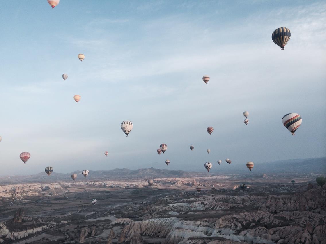 Hot air balloons drifting over the Cappadocia valleys at dawn